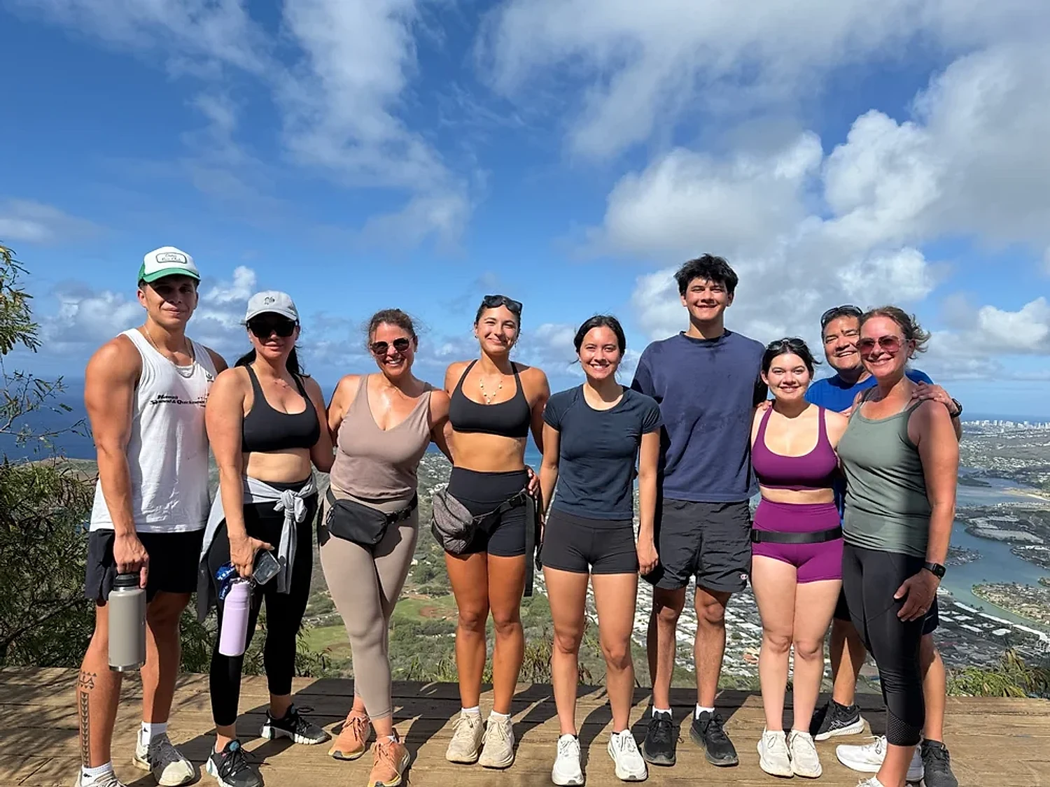 A group of hikers smiling together on an O'ahu summit